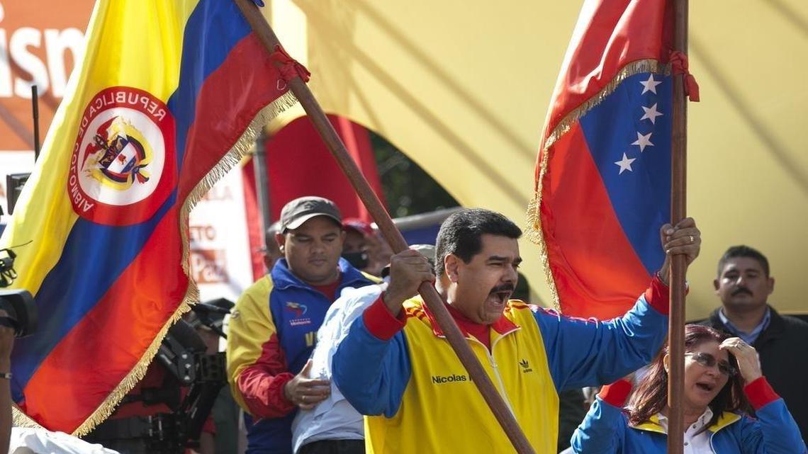 El gobernante venezolano Nicolás Maduro ondea simultáneamente las banderas de Venezuela y de Colombia durante un evento en el que buscaba respaldo para su decisión de cerrar la frontera entre los dos países. Curiosamente, investigaciones recientes apuestan a que el mandatario podría contar con la doble nacionalidad, tras haber nacido en Bogotá, lo que le inhabilitaría legalmente para ejercer la presidencia.