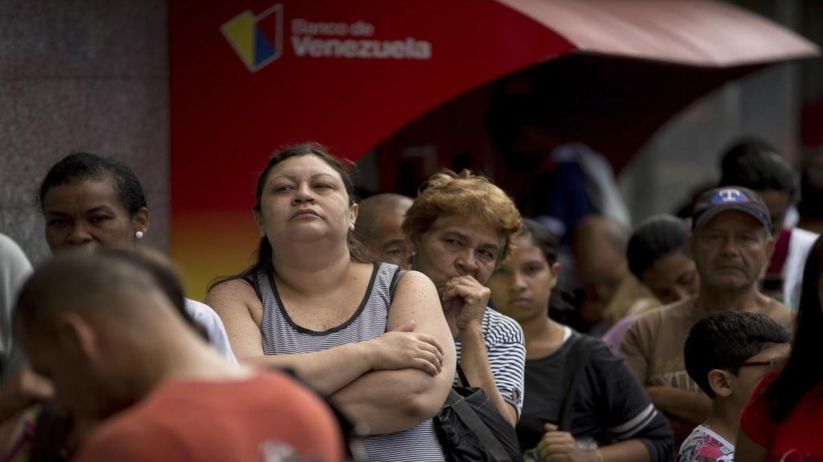 Un grupo de personas espera en una fila afuera de una sucursal del Banco de Venezuela en Caracas para cambiar billetes de 100 bolívares, después de que el gobierno ordenada que salgan de circulación.