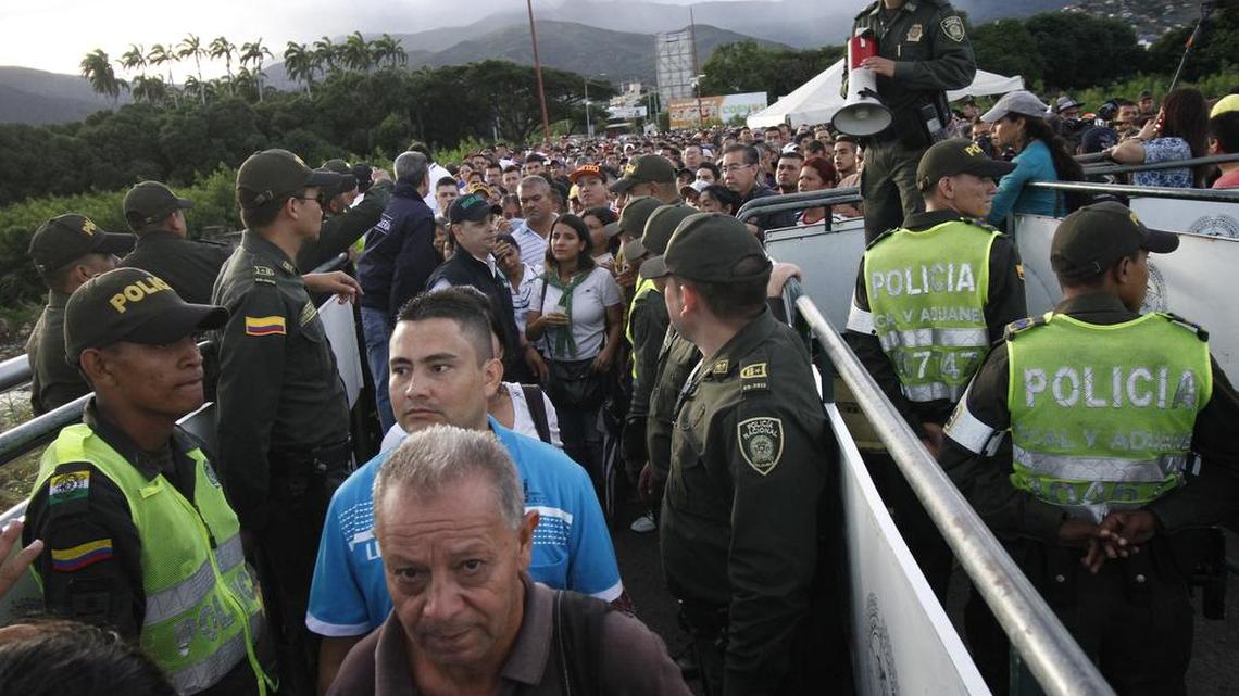 Policías colombianos montan guardia mientras miles venezolanos cruzan la frontera en busca de alimentos y medicinas.