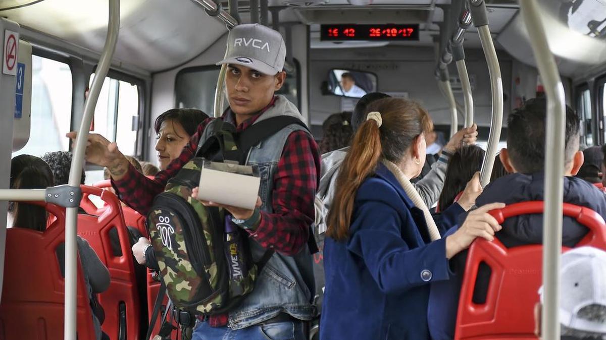 El venezolano Jhonger Piña, de 25 años, vende velas y muestra billetes de bolívar como curiosidad en un autobús de transporte público en Bogotá.