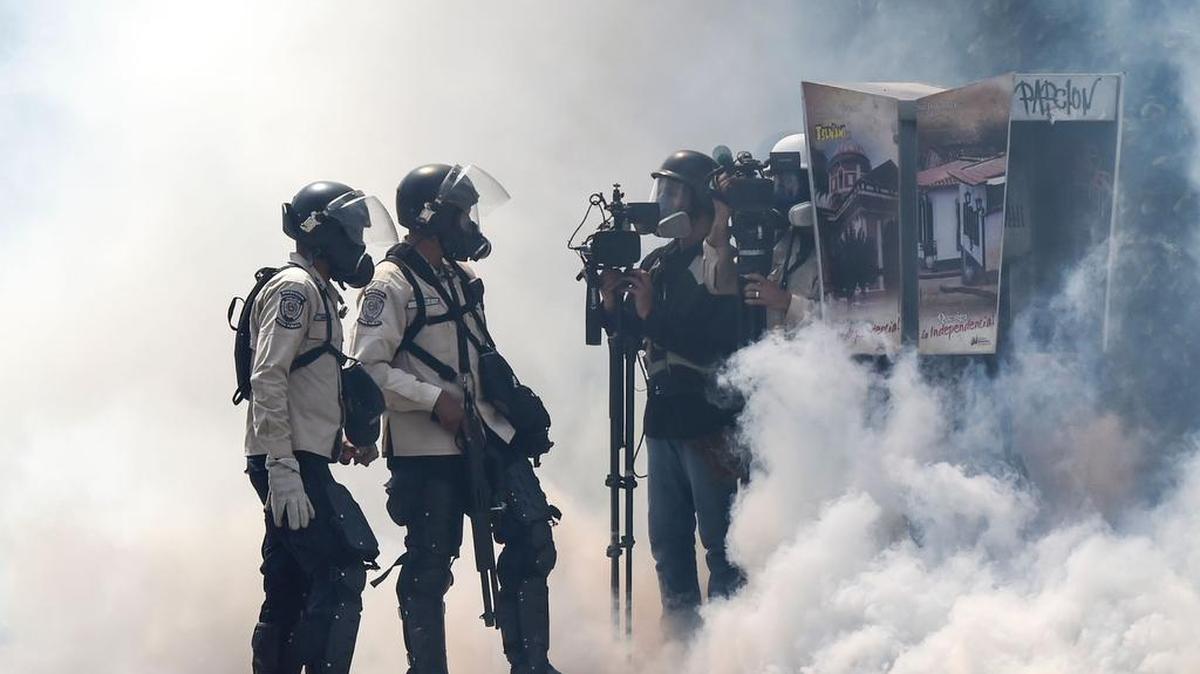 Policías y periodistas en medio de una nube de gases lacrimógenos durante una protesta contra el gobierno del presidente Nicolás Maduro en Caracas el 8 de abril de 2017.