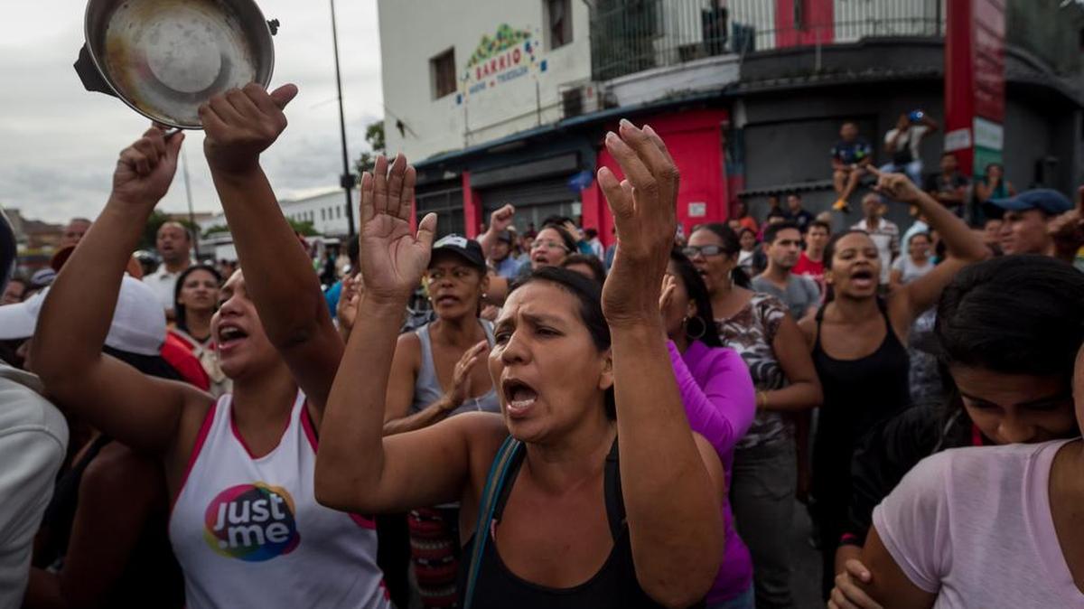 Un grupo de personas protesta exigiendo comida en el sector popular Catia, en Caracas. Nuevos focos de protestas e intentos de saqueos se desarrollaron en varios estados de Venezuela.