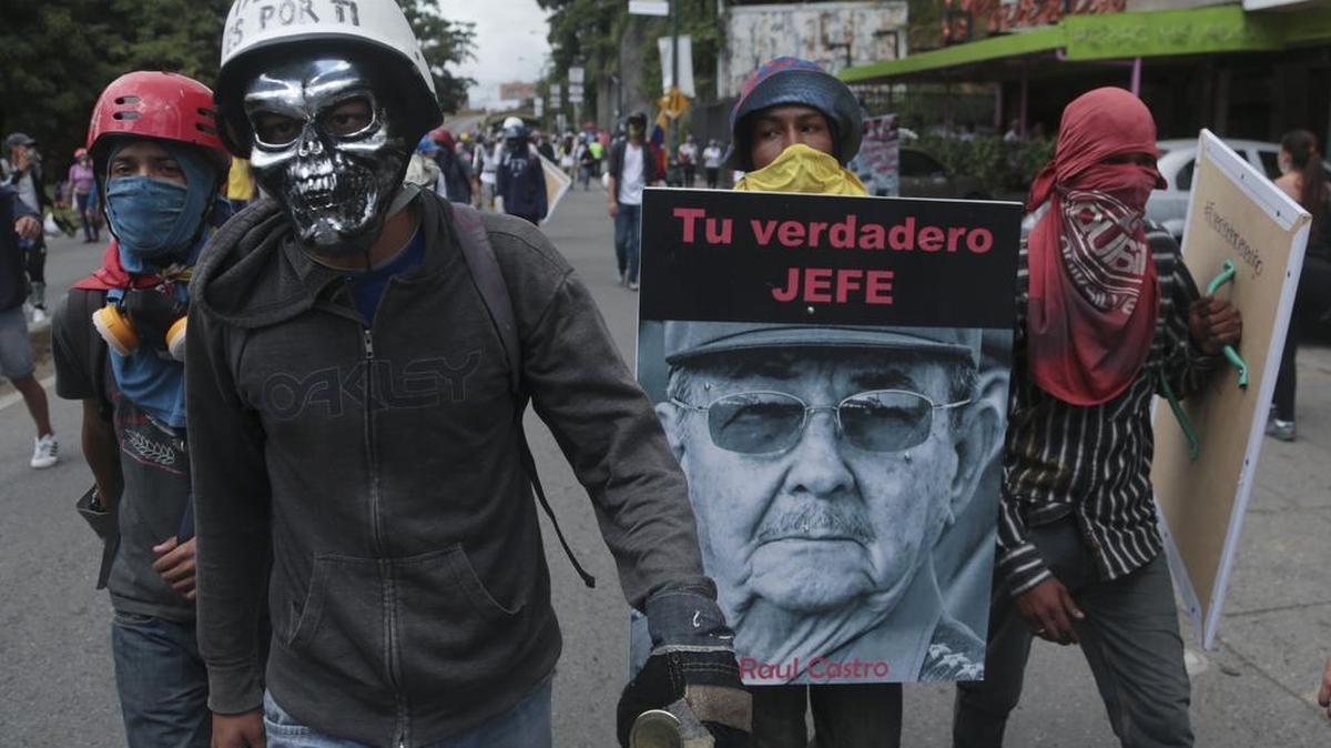 Manifestantes llevan un cartel con un retrato del gobernante cubano Raúl Castro en Caracas, Venezuela, el sábado 10 de junio de 2017.