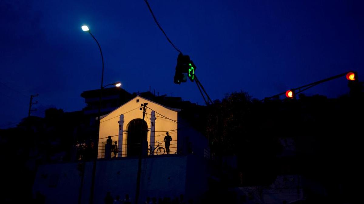 Foto del 23 de abril de 2016, se observa las figuras de residentes en la fachada de una iglesia, el único edificio iluminado después de un apagón de 24 horas, en el barrio El Calvario de El Hatillo, en las afueras de Caracas, Venezuela.