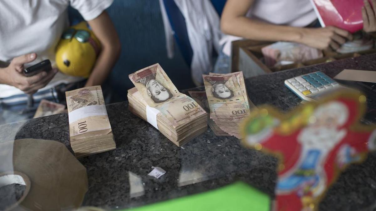 Empleados de una agencia de lotería organizan billetes de 100 bolívares el lunes en Caracas, Venezuela.
