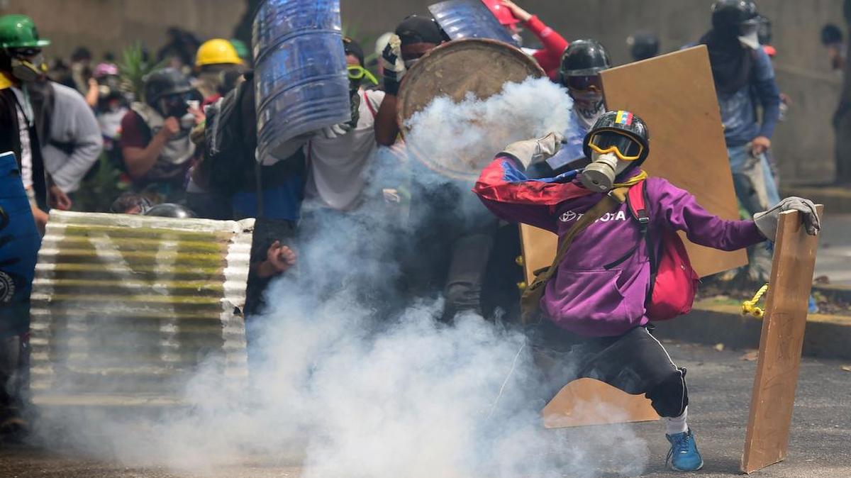 Un activista de la oposición en Venezuela devuelve una bomba de gas lacrimógeno durante una marcha en Caracas contra el gobierno de Nicolás Maduro el 1 de mayo del 2017.