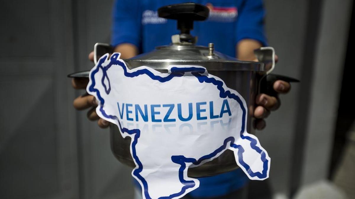 Miembros del partido político Un Nuevo Tiempo sostienen una olla a presión que simboliza la situación del país a la entrada de una de las sedes del Consejo Nacional Electoral (CNE) el miércoles 10 de agosto del 2016, en Carcas (Venezuela).