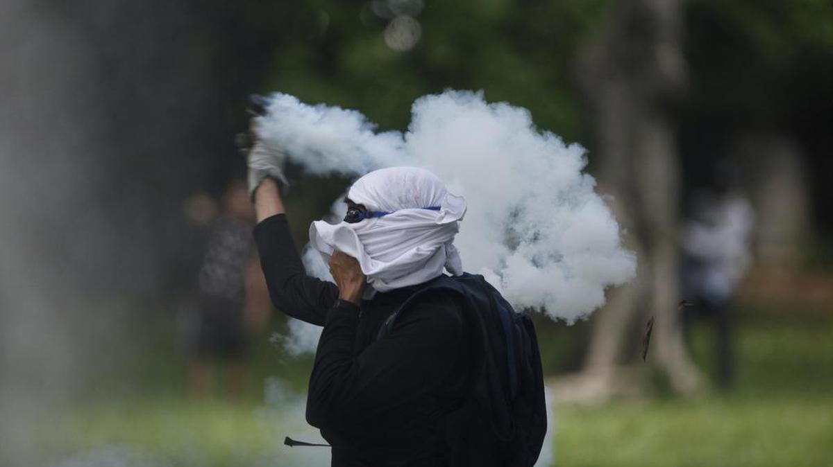 Un estudiante devuelve una granda de gases lacrimógenos que lanzara el jueves la policía contra los manifestantes en la Universidad Central en Caracas.