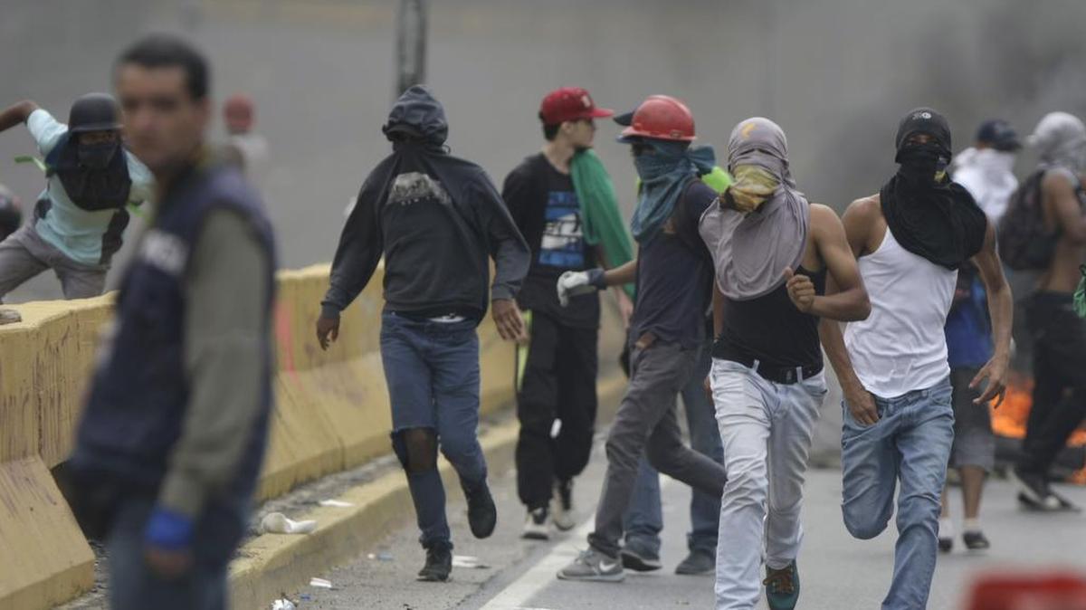 Los manifestantes corren en una carretera cerrada durante una protesta nacional contra el presidente Nicolas Maduro, en Caracas, Venezuela, el lunes 15 de mayo de 2017.