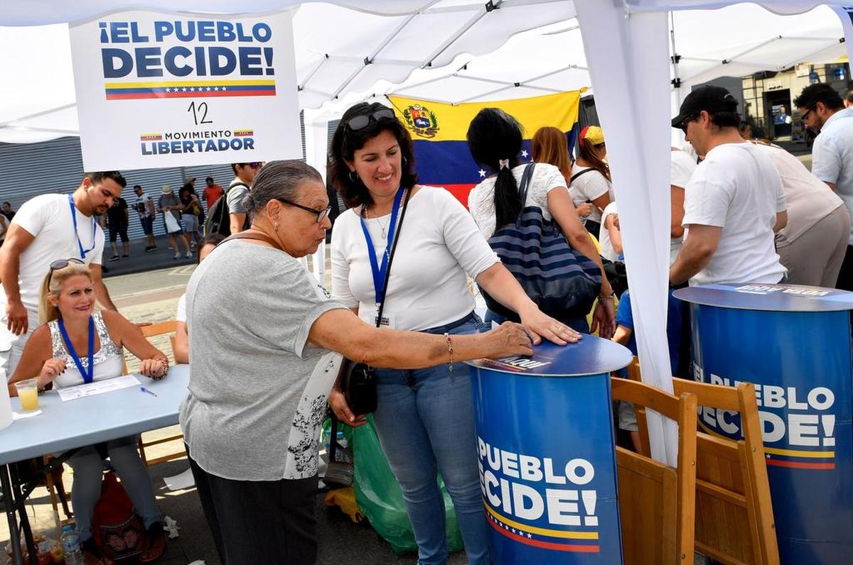 Una residente venezolana en Madrid coloca su voto en una mesa de votación durante un plebiscito celebrado en la Puerta del Sol de Madrid el 16 de julio de 2017 .