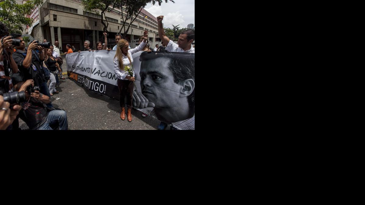 
Lilian Tintori (2d), esposa del dirigente de la oposición venezolana, Leopoldo López, junto a una pancarta con la imagen de éste, a las afueras del Palacio de Justicia hoy, martes 30 de septiembre de 2014, donde continúa el juicio penal contra López, en la ciudad de Caracas (Venezuela).
