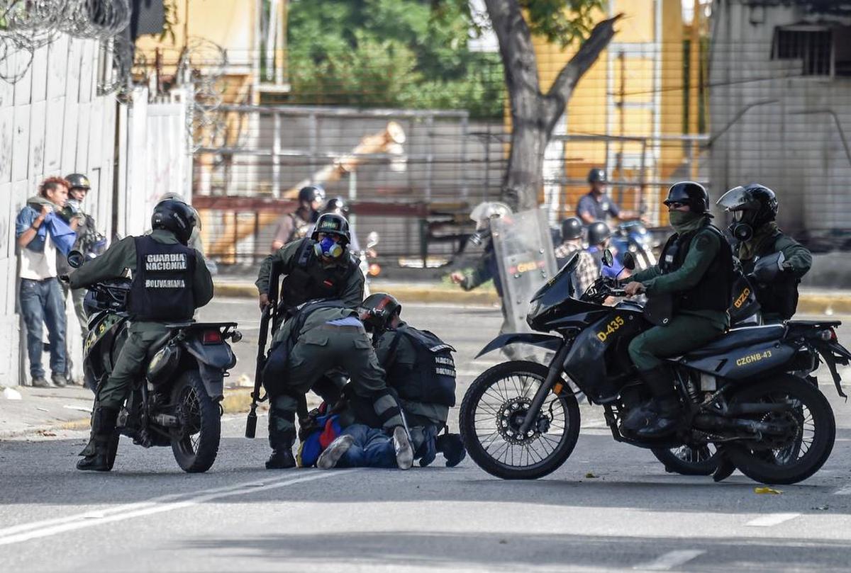 Miembros de la Guardia Nacional Bolivariana detienen a un manifestante opositor en una calle de Caracas, Venezuela, el lunes 26 de junio de 2017.