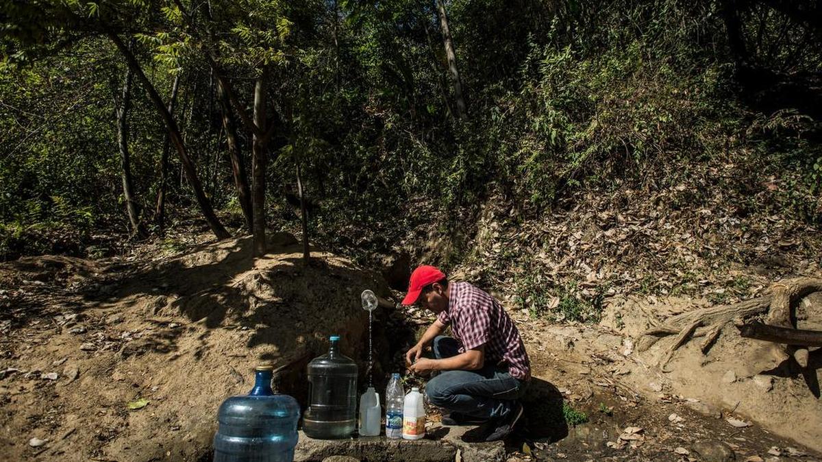 Fernando Zambrano llena jarras con agua de una montaña, en el barrio La Pastora de Caracas, Venezuela, 23 de enero de 2016.