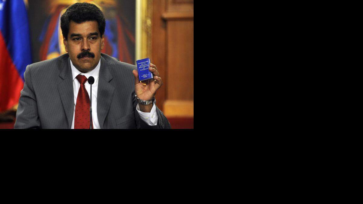 
El presidente venezolano Nicolás Maduro muestra la Constitución de la República en una conferencia de prensa en Miraflores en marzo.
