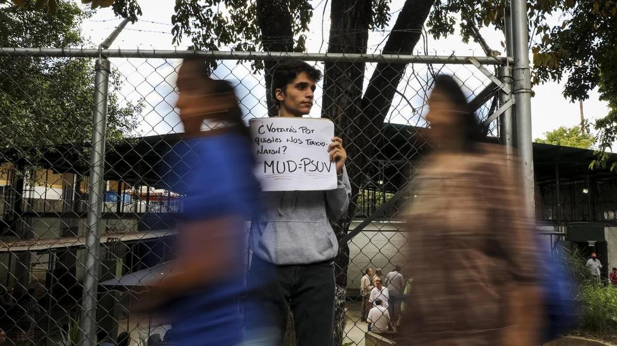 Un joven porta un cartel en el que se lee "¿Votarías por quienes nos traicionaron? MUD = PSUV" el domingo 10 de septiembre del 2017, durante la jornada de votación de las primarias de la alianza Mesa de la Unidad Democrática (MUD), en Caracas (Venezuela).
