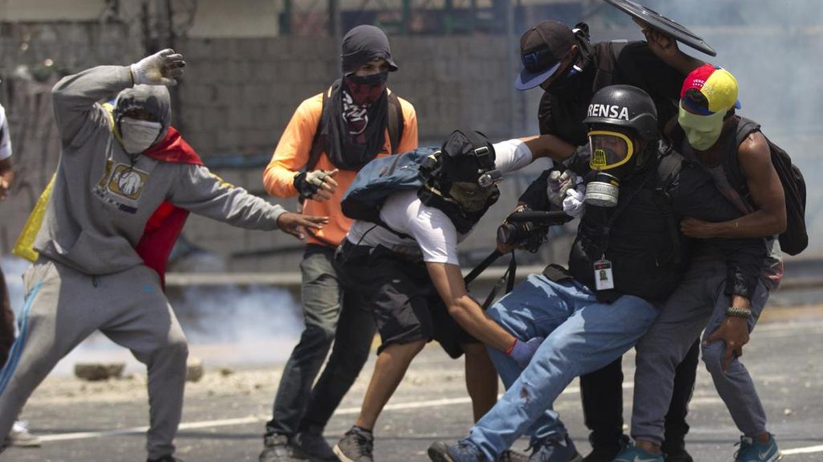 Los manifestantes ayudan a un periodista que fue lesionado en una pierna mientras cubría los enfrentamientos entre manifestantes y la Guardia Nacional Bolivariana durante una protesta en Caracas, Venezuela, el lunes 10 de abril de 2017.