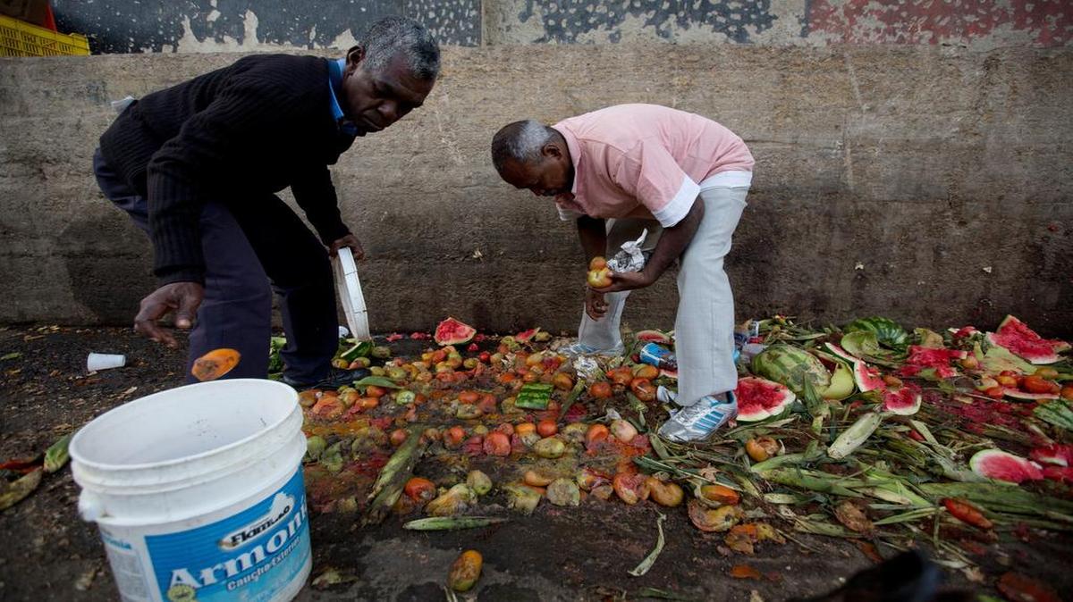 Pedro Hernández (izq) y su amigo Luis Daza recogen tomates en un basurero del mercado público de Coche en Caracas.