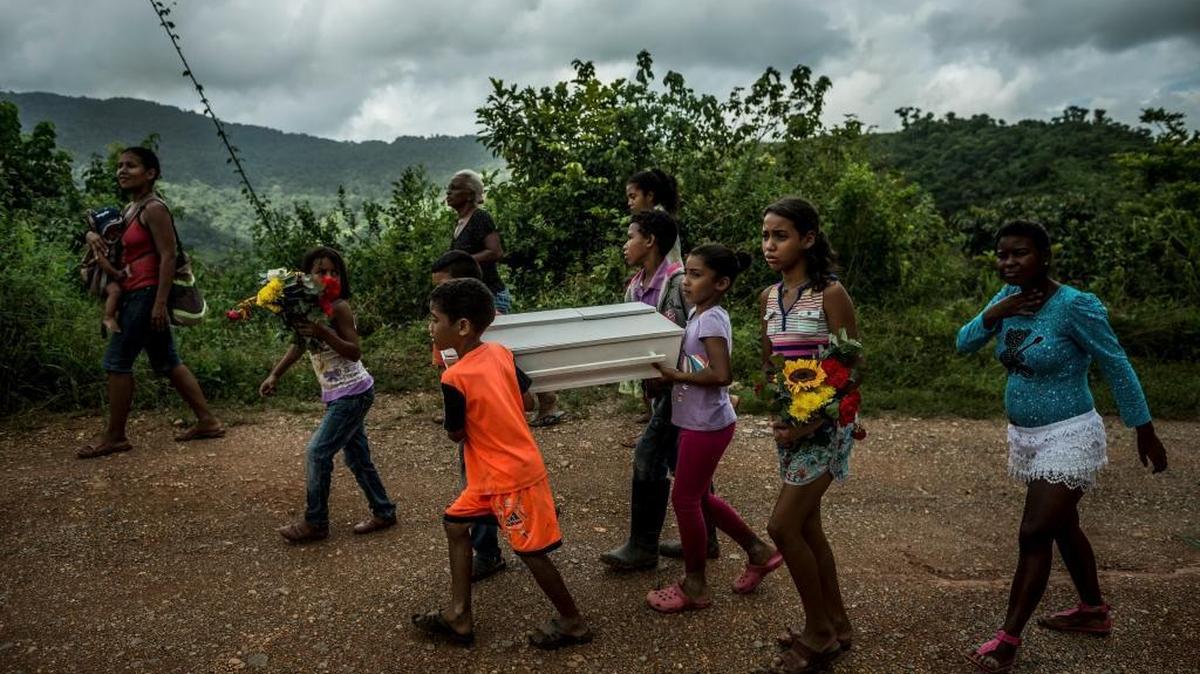 Niños transportan el ataúd de Kleiver Enrique Hernández, de 3 meses de edad, en un viaje de más de dos horas y media, sobre colinas y arroyos de poca profundidad, hasta el cementerio desde su casa en Urdaneta, Venezuela, el 17 de agosto del 2017.