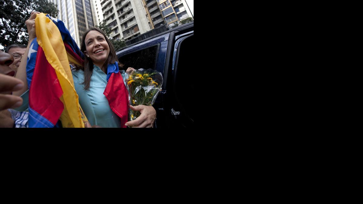 
La ex diputada María Corina Machado sostiene en sus manos la bandera venezolana mientras saluda a sus simpatizantes a la salida de la Fiscalía General en Caracas el miércoles.
