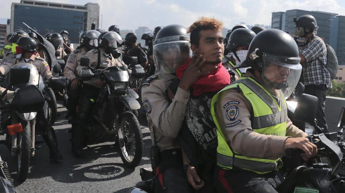 Agentes de la Policía Nacional Bolivariana transportan en una motocicleta a un manifestante detenido en Caracas, Venezuela.