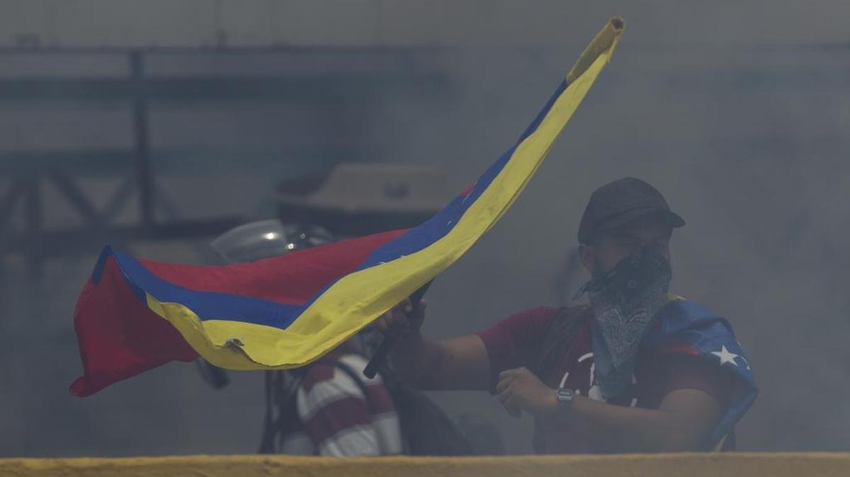 Un manifestante agita una bandera nacional venezolana envuelta en una nube de gases lacrimógenos lanzada por la Guardia Nacional Bolivariana en una protesta en Caracas, Venezuela, el lunes 10 de abril de 2017.