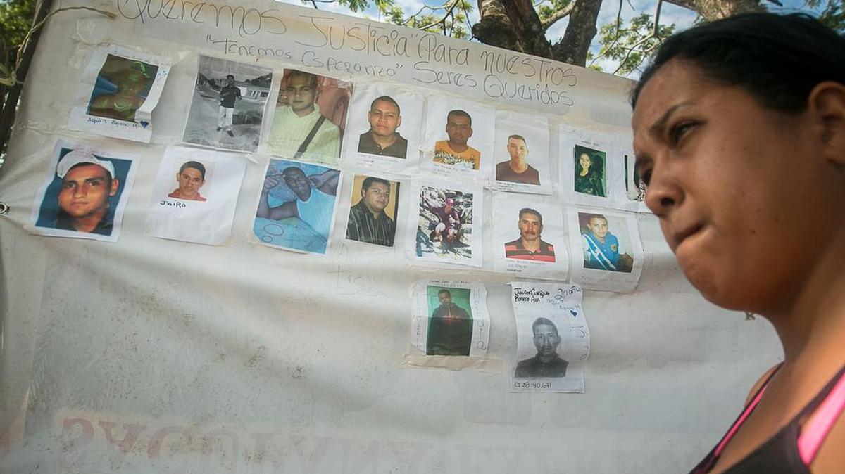Una mujer camina junto a un cartel con fotografías de los mineros desaparecidos, el 9 de marzo de 2016, en la localidad de Tumeremo, en el estado Bolivar (Venezuela).