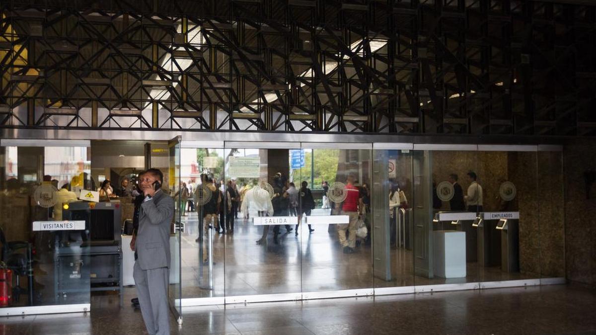 Trabajadores del Banco Central de Venezuela (BCV) permanecen el lunes 20 de junio del 2016, en el interior del edificio en donde un hombre armado hiriò a dos guardias de seguridad en Caracas (Venezuela). 