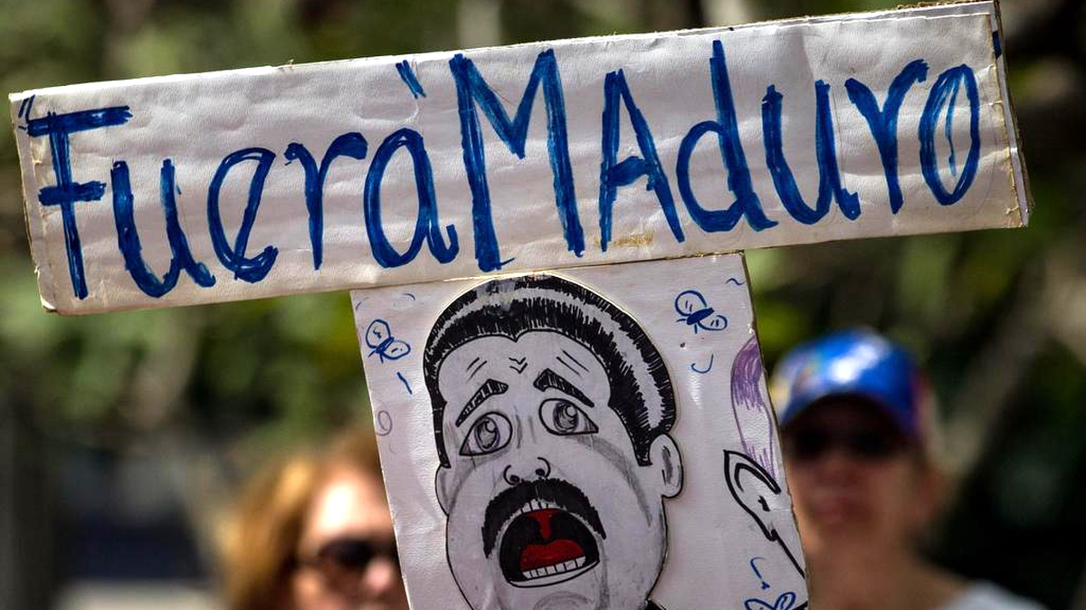 Un grupo de opositores protestan con pancartas en donde se lee "Fuera Maduro" el martes 20 de diciembre del 2016, en Caracas (Venezuela).