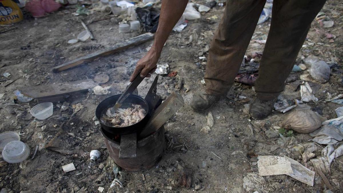 Un hombre cocina un pellejo de pollo que encontró en un basurero en Puerto Cabello, Venezuela, el 1 de noviembre del 2016.