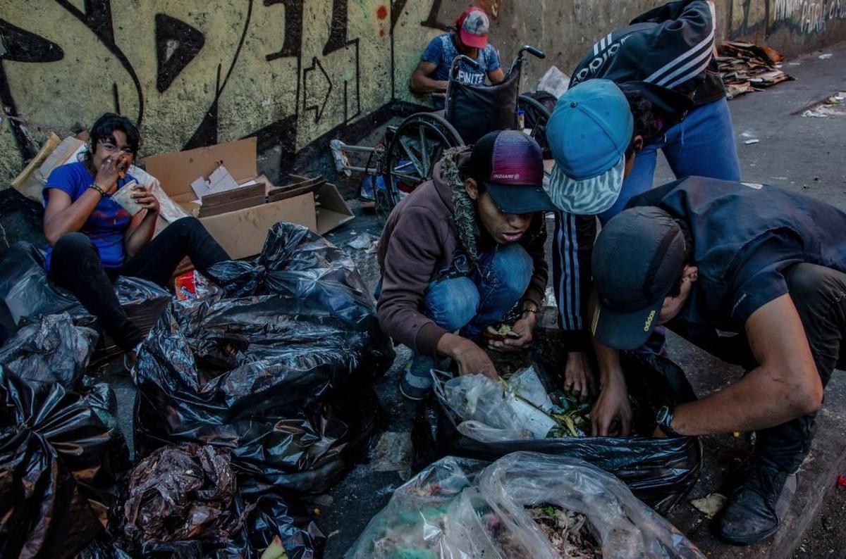 Una escena que raramente se veía antes de la crisis: algunas familias buscan comida entre la basura en Caracas.