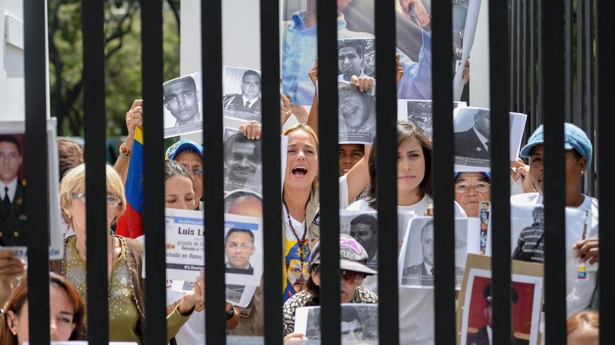 La esposa del líder de la oposición venezolana Leopoldo López, Lilian Tintori (C), junto a la alcaldesa de San Cristóbal Patricia de Ceballos y familiares de presos políticos se posan dentro de una simulación de prisión durante una protesta frente a la Nunciatura en Caracas el 10 de noviembre de 2016.