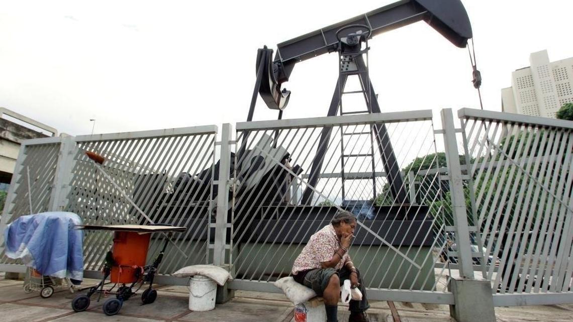 La desamparada Carmen Elena Sánchez fuma junto a una escultura de un perforadora de petróleo en Caracas, Venezuela.