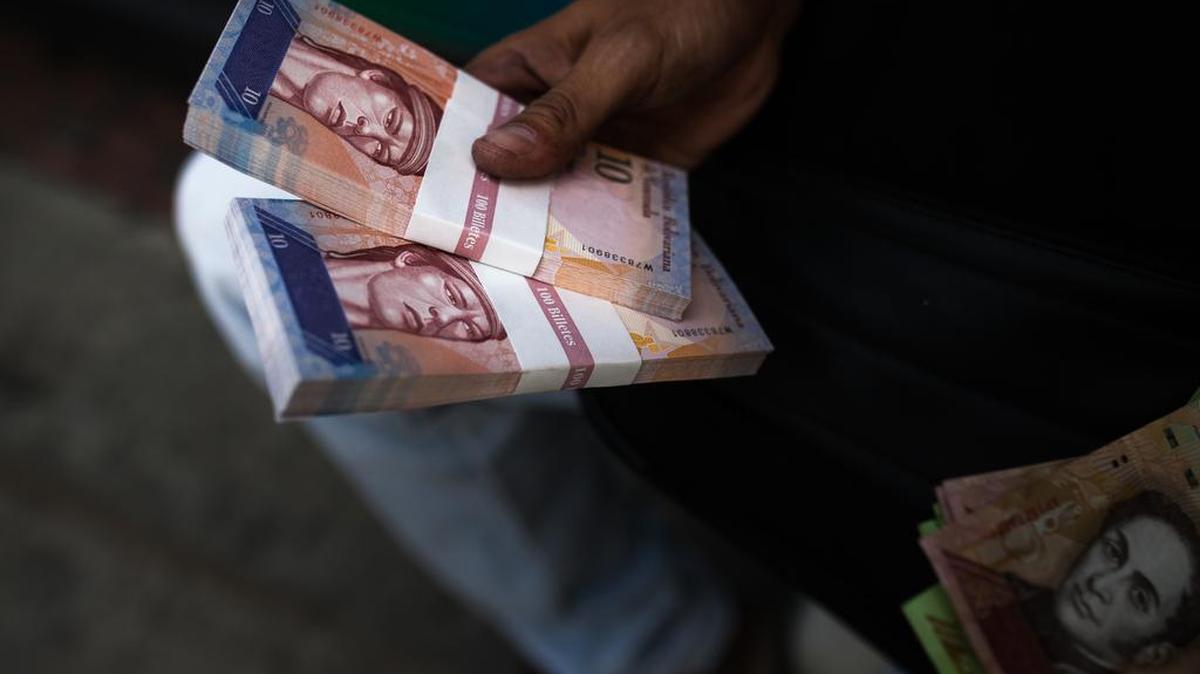 Un hombre muestra billetes de 10 bolívares que recibió después de cambiar las notas de 100 bolívares, el miércoles en Caracas.