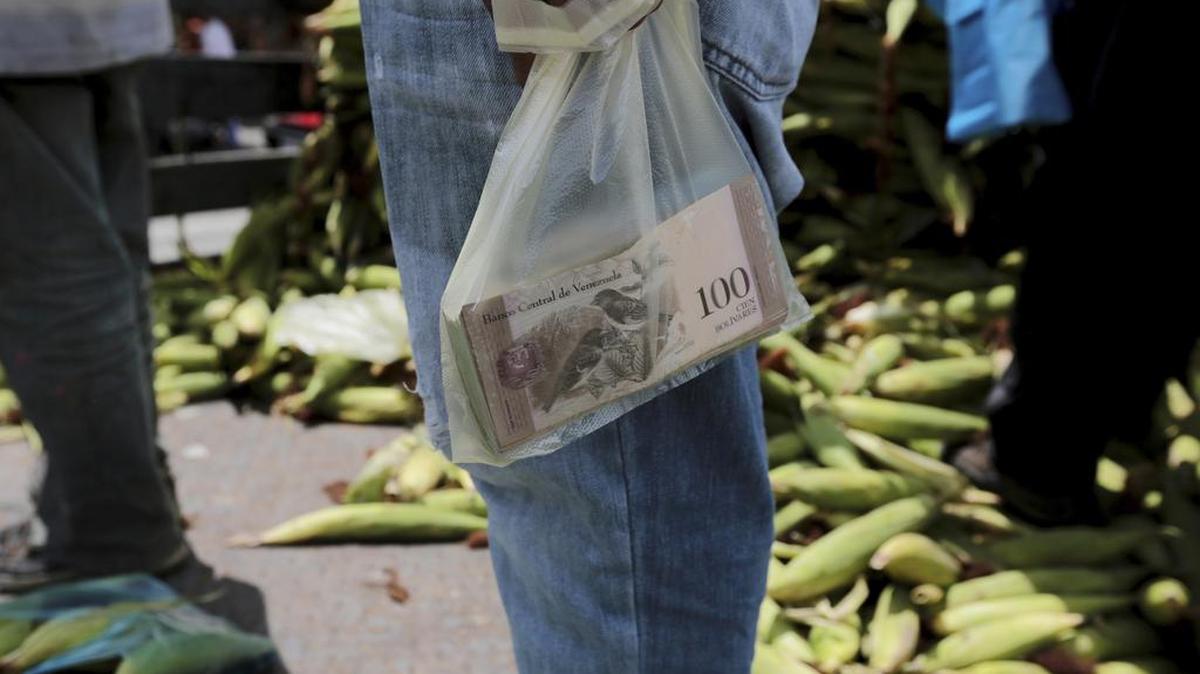 En medio de la escasez de alimentos, medicinas y otros productos de alta necesidad, hay que añadir la falta de efectivo en Venezuela. En la foto, un vendedor guarda su efectivo en una bolsa plástica en un mercado de Caracas.