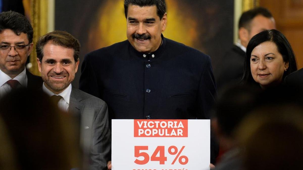 Esta foto de archivo tomada el 17 de octubre de 2017 muestra al presidente venezolano, Nicolás Maduro (C), con un letrero después de una conferencia de prensa con medios internacionales en Palacio Presidencial de Miraflores en Caracas.