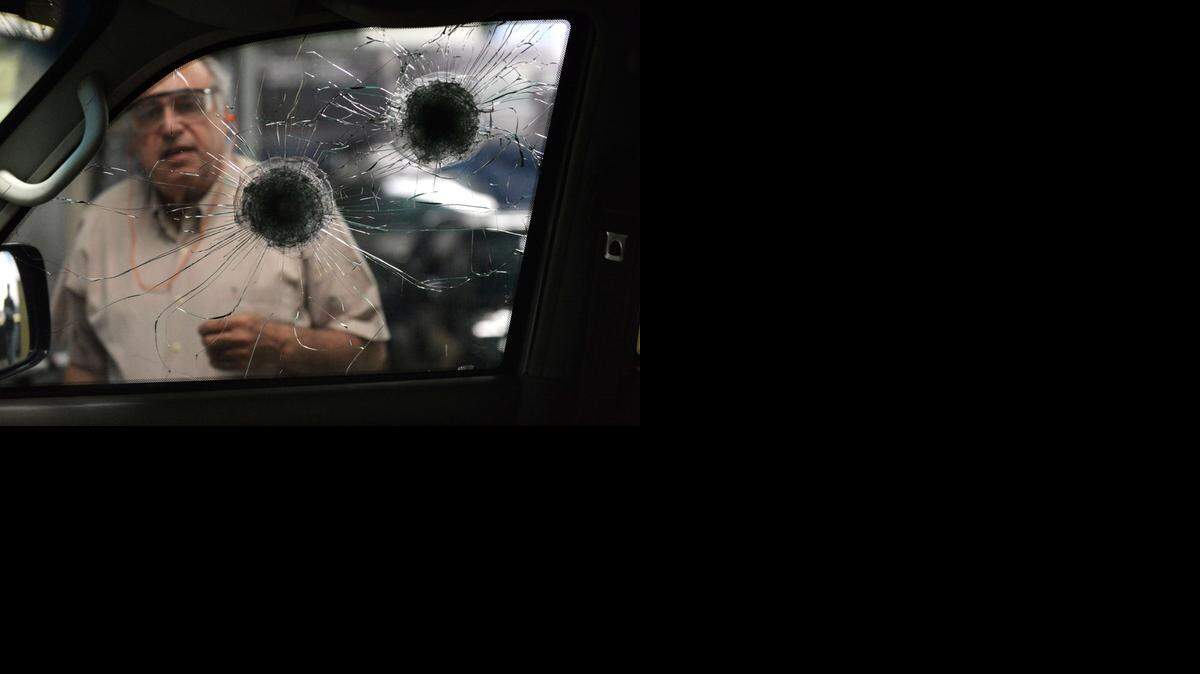 
Un trabajador revisa las ventanas blindadas con disparos de bala en un garaje de vehículos blindados en Caracas , el 21 de octubre de 2014.
