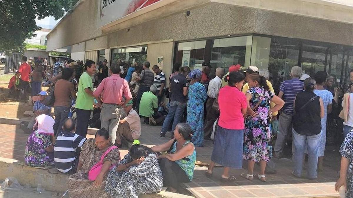 Venezolanos de la tercera edad hacen fila en un banco de Maracaibo para cobrar la pensión mensual del gobierno.