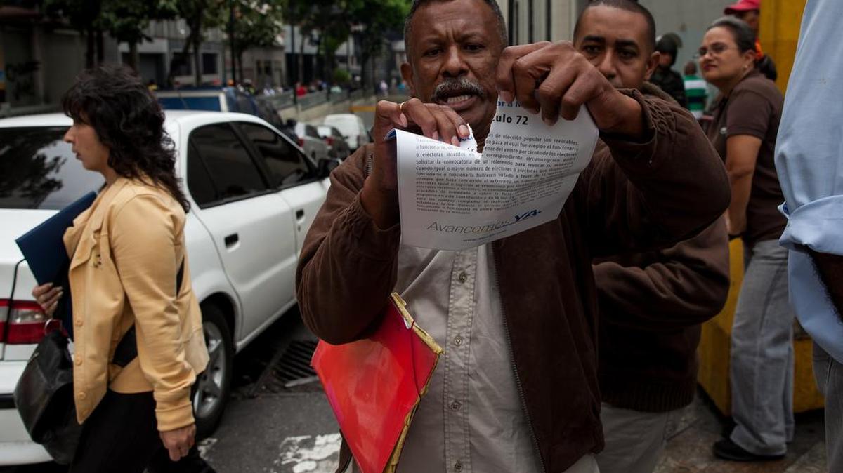 Un chavista rompe un documento que entrega la oposición durante choques entre miembros de la oposición y el chavismo, frente a las inmediaciones del Consejo Nacional Electoral (CNE) cuando los opositores acudían a la sede del organismo electoral para pedir el documento del referendo revocatorio, hoy, jueves 7 de abril del 2016, en Caracas (Venezuela). La alianza opositora venezolana Mesa de la Unidad Democrática (MUD) solicitó hoy al CNE entregar los formularios que darán inicio al referendo revocatorio, una de las medidas con las que pretenden adelantar la salida del gobierno de Nicolás Maduro, según informó el secretario ejecutivo de la coalición, Jesús "Chúo" Torrealba.