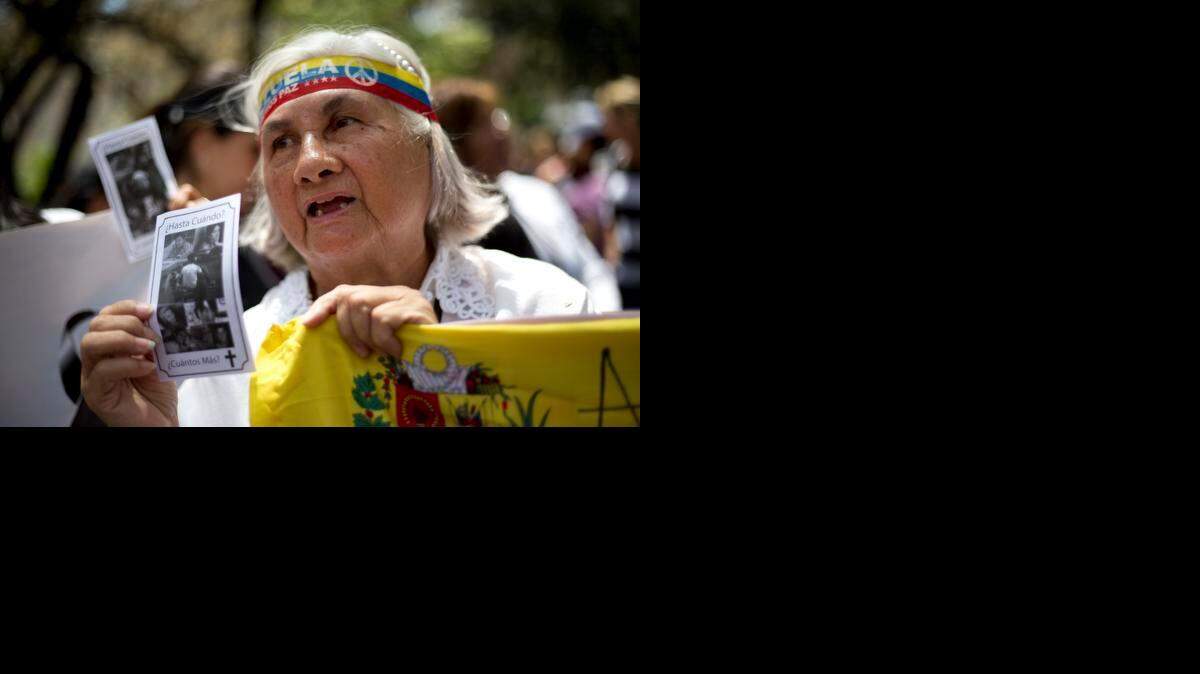 
Una mujer muestra una foto con varias personas que han muerto en protestas antigubernamentales, el miércoles en Caracas. 
