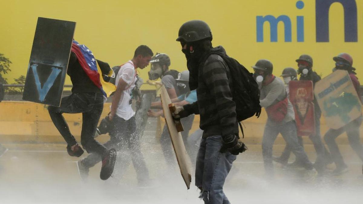 Manifestantes antigubernamentales usan escudos caseros para cubrirse de un cañón de agua lanzado por las fuerzas de seguridad en Caracas, Venezuela, el lunes 8 de mayo de 2017.