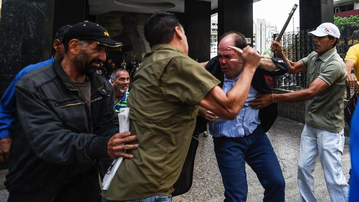 Agentes del gobierno de Nicolás Maduro golpean el jueves al diputado opositor Julio Borges, durante una protesta ante el Consejo Nacional Electoral.