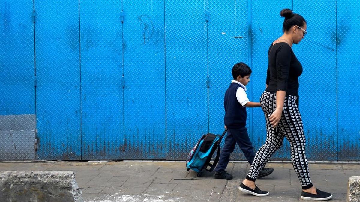 Karelys Rojas lleva a su hijo a la escuela en el barrio San Juan de Caracas, Venezuela.