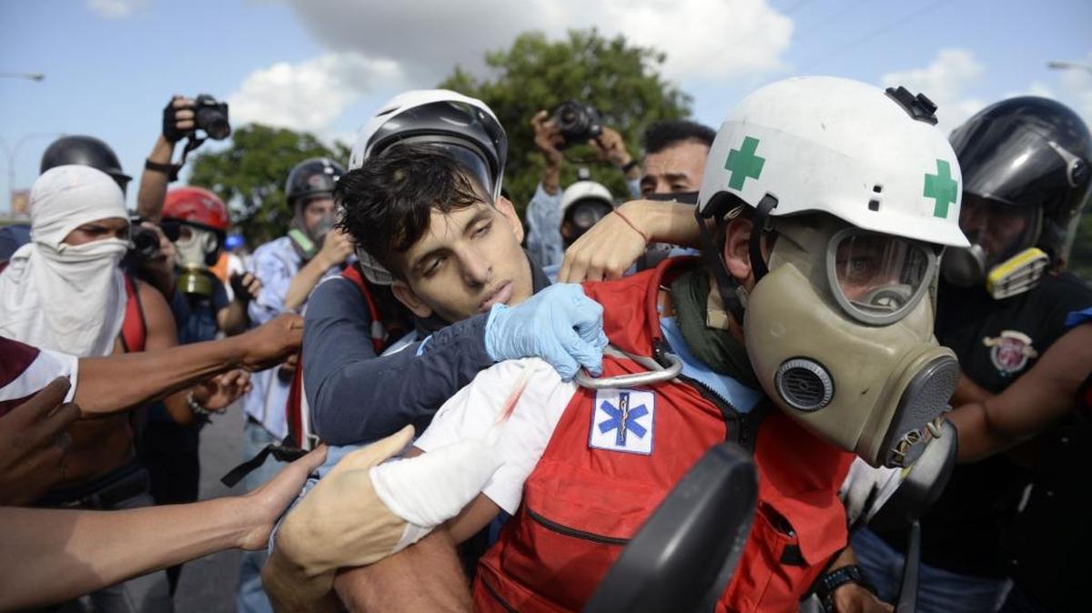 Un manifestantes herido por la policía con perdigón es llevado por voluntarios médicos en una protesta en Caracas el 22 de junio.