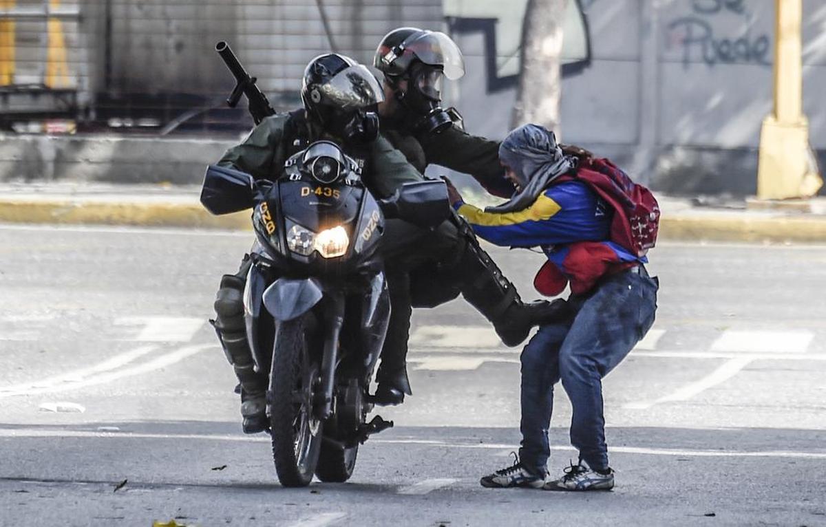 Miembros de la Guardia Nacional Bolivariana detienen a un manifestante opositor por una calle de Caracas, Venezuela, el lunes 26 de junio de 2017.
