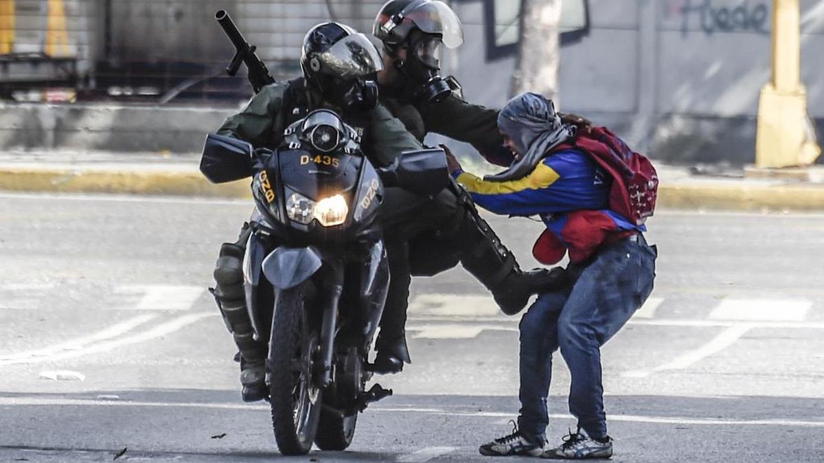 Miembros de la Guardia Nacional Bolivariana detienen a un manifestante opositor por una calle de Caracas, Venezuela, el lunes 26 de junio de 2017.