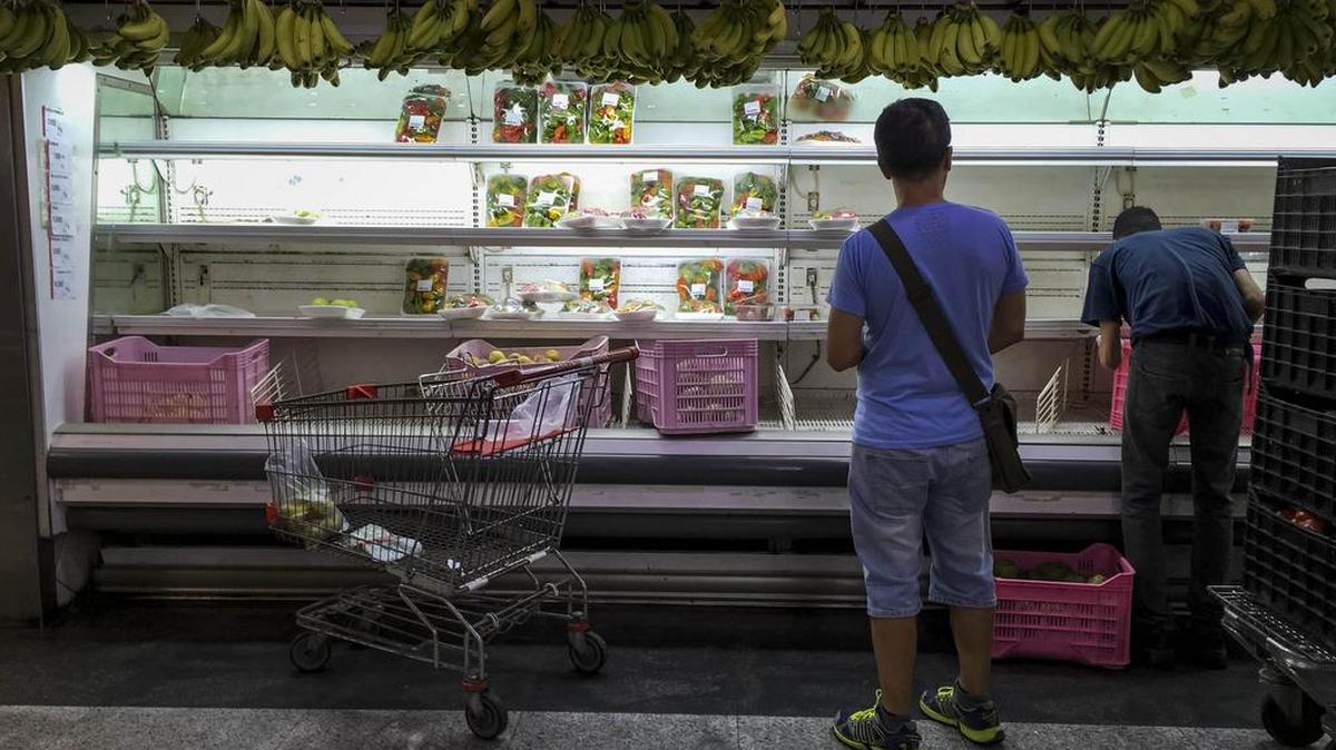 Personas buscan alimentos en un supermercado con estanterías parcialmente vacíos el lunes 24 de julio de 2017, en Caracas.