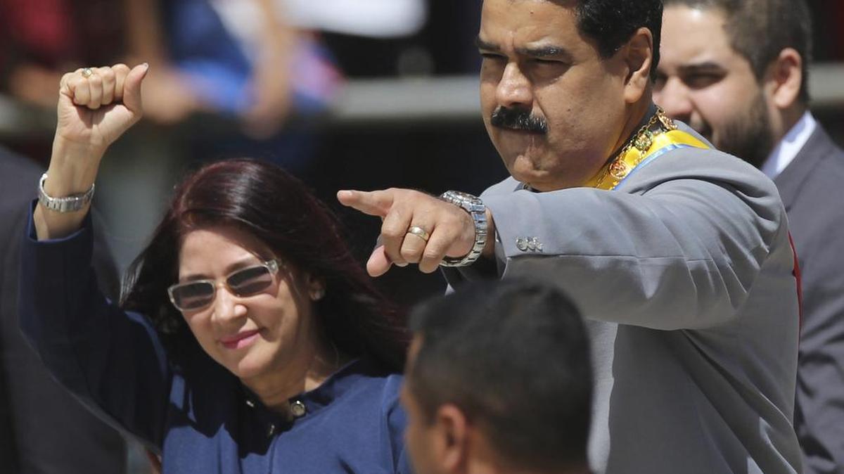En esta foto de archivo del 1 de febrero de 2017, el presidente de Venezuela, Nicolás Maduro, y la primera dama Cilia Flores saludan a los simpatizantes a su llegada a un desfile militar en el Fuerte Tiuna en Caracas, Venezuela.