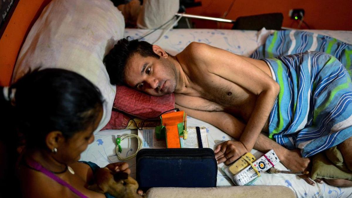 Daikellys Mosquera de 13 años, habla con su padre tetrapléjico Marco Guillén en su casa en Barquisimeto, estado de Lara, Venezuela el 23 de octubre de 2017.
