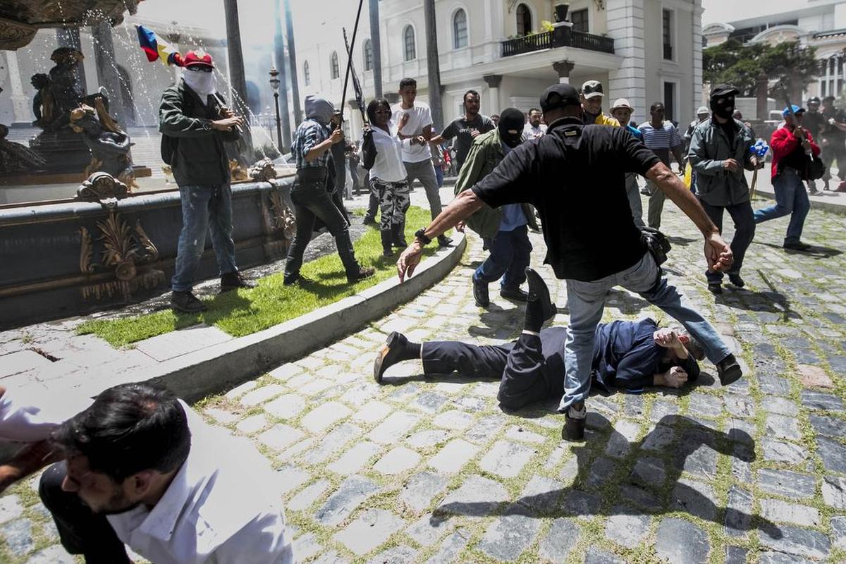 Los diputados Armando Armas (i) y Américo De Grazia (c) son golpeados por manifestantes en el piso en la Asamblea Nacional el miércoles 5 de julio de 2017, en Caracas (Venezuela).