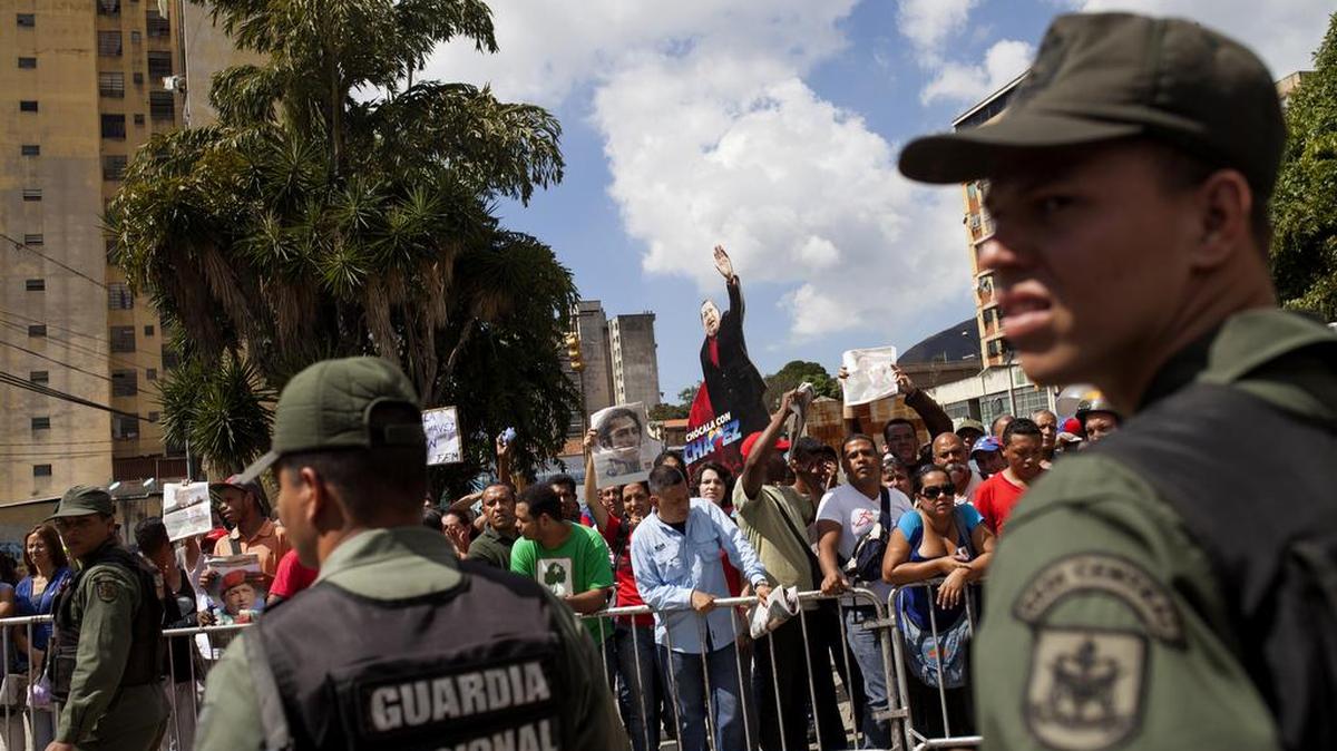 Miembros de la Guardia Nacional observan una protesta de los seguidores del oficialismo afuera el Tribunal Supremo.
